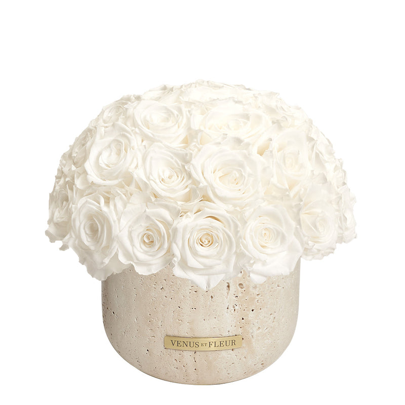 Bouquet of white roses in a stone vase with a label reading 'VENUS ET FLEUR'