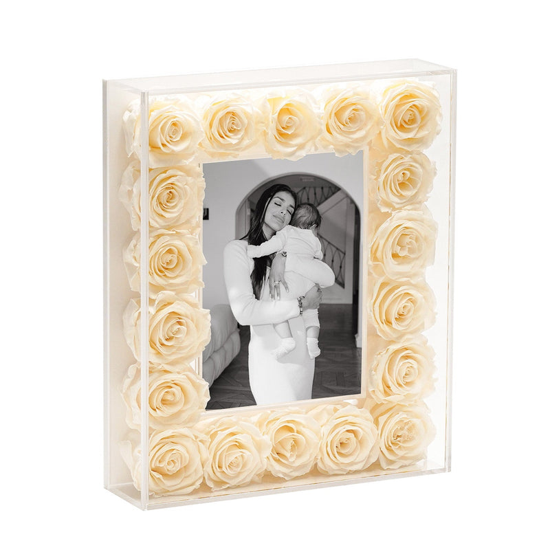 Square clear photo frame filled with cream-colored roses surrounding a black and white photo of a woman holding a baby.
