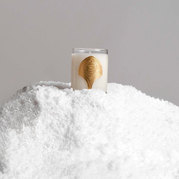 White candle with a gold label reading 'ETERNITY RING VENUS FLORA' placed on a mound of white powdery substance.